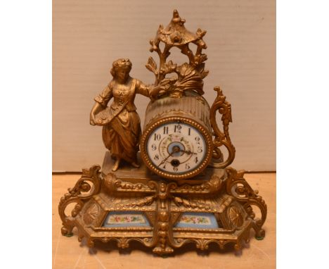 A late 19th/early 20th century gilt spelter figural mantel clock with painted porcelain panels, the circular painted dial set