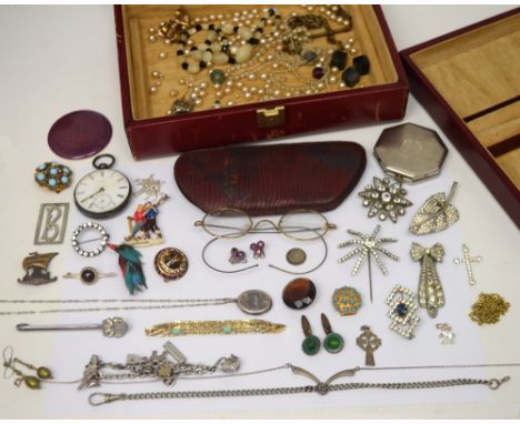 A fitted leather jewellery box containing a selection of dress jewellery to include a silver locket and chain, a charm bracel