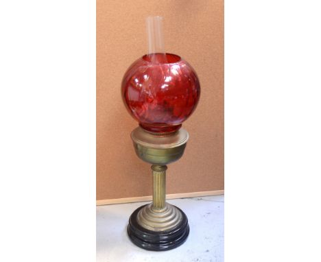 An Edwardian brass reeded column oil lamp on stepped circular base with a circular rouge glass shade.