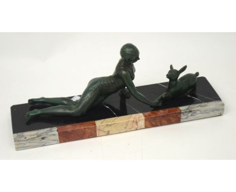 An Art Deco figural sculpture, marble rectangular base with a reclining scantily-clad young lady playing with a deer, length 