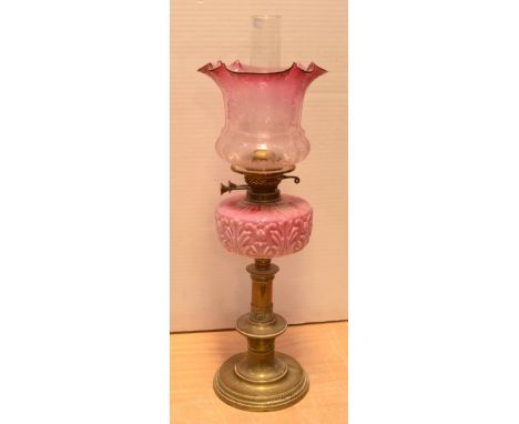 A Victorian brass oil lamp with floral moulded pink glass reservoir, engraved pink tinted glass shade with chimney and duplex