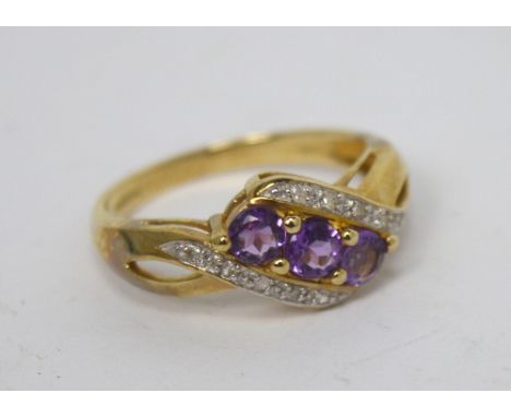 A 9ct gold dress ring set with three central amethyst-coloured stones with small diamond chips on a twist, size P, approx 2.9