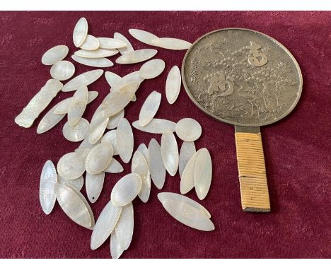 A antique bronze Chinese hand mirror and a selection of antique MOP gaming tokens 