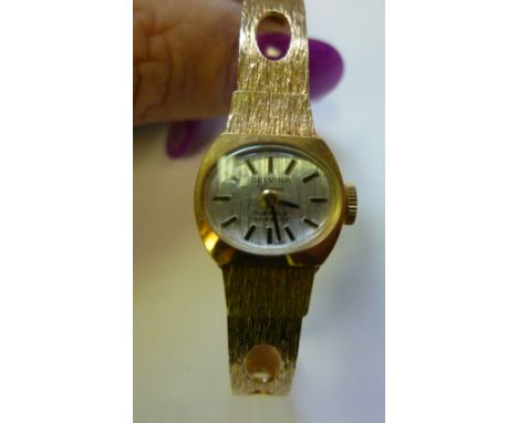 A lady's Delvina Incabloc yellow metal, round cased wristwatch, faced in a baton dial, on a textured bark effect bracelet