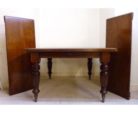 A late Victorian walnut extending dining table, the top having canted corners, raised on reeded, ring turned, tapered legs an