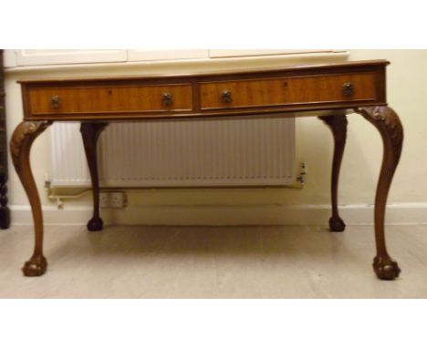 A mid 20thC walnut writing table, the top having a thumb moulded edge, over two shallow, in-line frieze drawers with cock bea