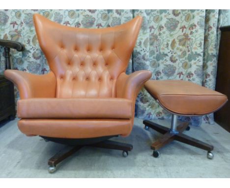 A 1960s G-Plan design, wing back armchair, part button upholstered in orange vinyl, rotating and raised on an exotic hardwood