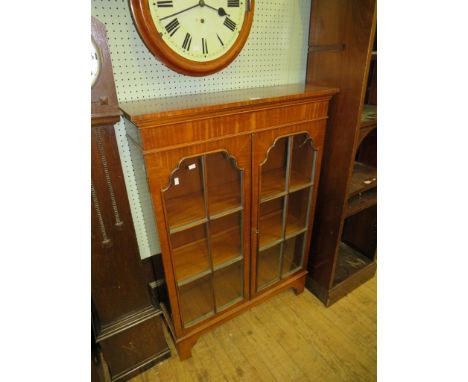 A small reproduction mahogany bookcase cabinet with two glazed doors raised on bracket feet 