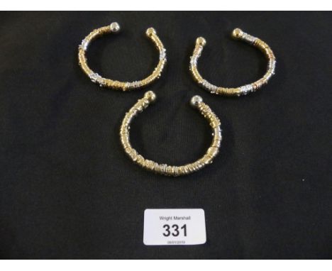 A set of three gold and base metal torque banglesEach designed as a base metal torque bangle with spherical terminals, and a 