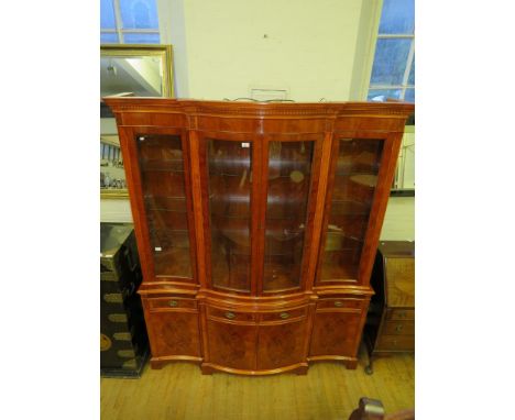 A good quality reproduction yew wood finished serpentine front display cabinet, with glazed four door top section over a base