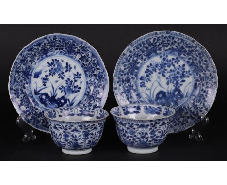 Two porcelain cups and saucers with tulip-shaped outer beds with floral decor, in the center a blossom-branch-on-a-rock decor