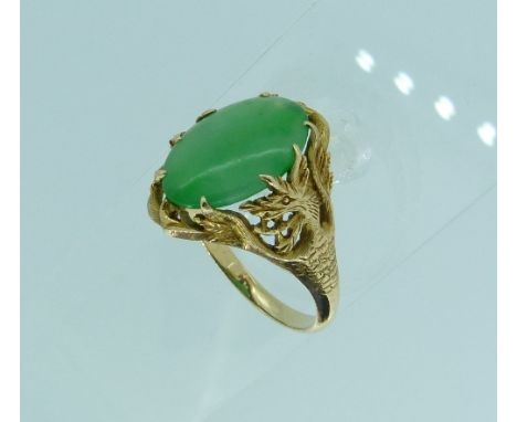 A Oriental style gold mounted jade Ring, the central oval stone mounted in yellow gold with the shoulders formed of pierced d