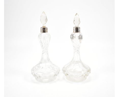 A pair of 1920s Art Deco silver collared cut glass bottles. The bottles having silver collars with faceted sides with etched 