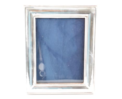 A silver hallmarked photo frame. The frame of rectangular shape with plain front and easel back. Hallmarked Birmingham, Ray H