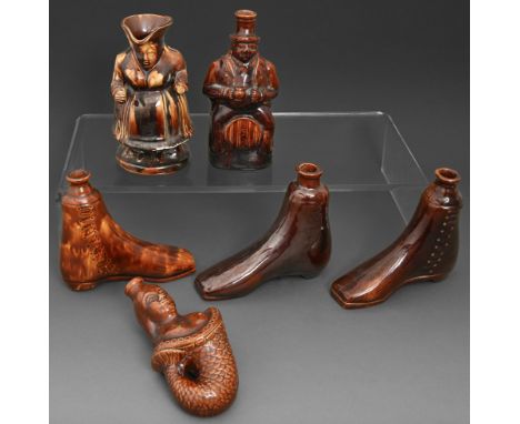 Five Victorian treacle brown glazed earthenware spirit flasks, mid 19th c, one in the form of a mermaid, and a female toby ju