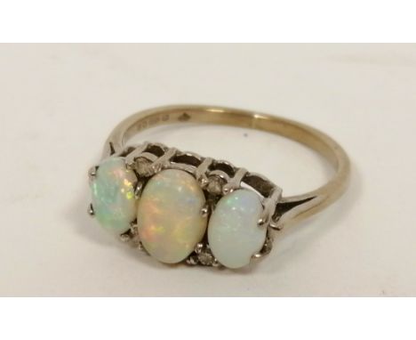 Opal three stone ring with eight cut diamonds in 18ct white gold, 1975. Size 'N'. 