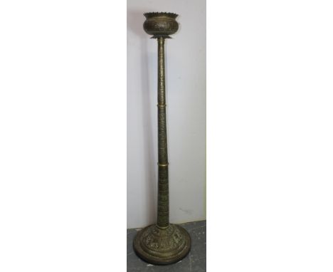 Indian brass floor standing temple lamp, the lotus shaped holder raised on embossed column depicting figures and foliage on s
