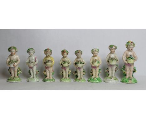 Seven 18th century Derby porcelain small figures of putti holding baskets of flowers, all with patch marks to base, the large