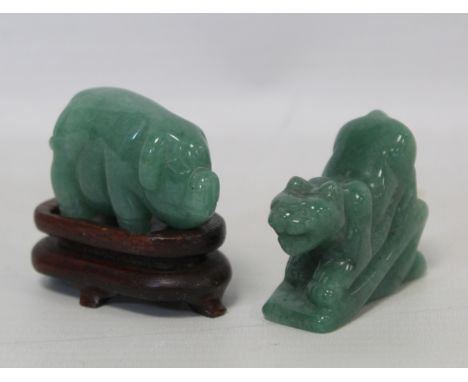 Two 20th century Chinese carved green jade figures of a crouching tiger, 4cm long and a pig on wooden stand, 4cm long.  (2). 