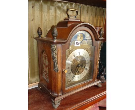 An Urgos arch topped bracket clock in a walnut-style case with ormolu mounts and finials, a silvered chapter ring and moon ph