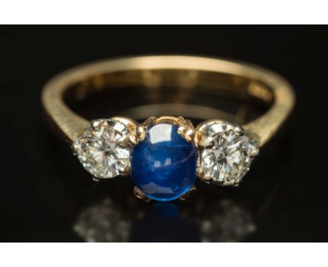 A sapphire and diamond three-stone ring: with central oval cabochon sapphire claw-set between brilliant-cut diamonds estimate