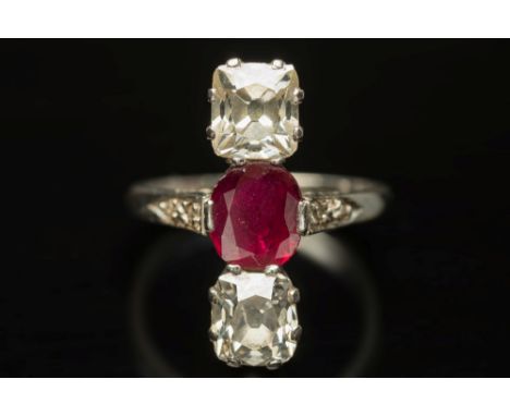 An 18ct white gold, ruby and diamond 'along the finger' three-stone ring: with central oval ruby approximately 6.8mm x 5.2mm,