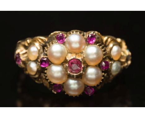 An antique gold, ruby and seed-pearl circular cluster ring:, with foliate engraved shoulders on fluted shank, circa 1850, rin