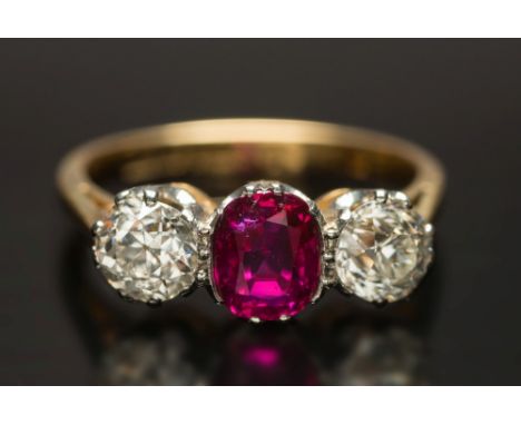 A gold, ruby and diamond three-stone ring: with central oval ruby, approximately 1.0ct between round old brilliant-cut diamon