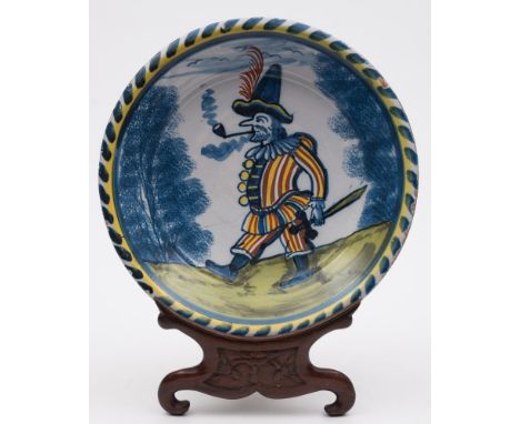 A rare English delftware blue-dash charger: painted in blue, yellow, iron-red and green with a figure representing Pulcinella