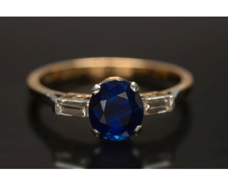 A sapphire and diamond three-stone ring: with central oval sapphire approximately 1.0cts in four-claw setting between baguett