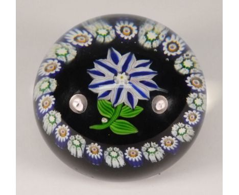 A Paul Ysart glass paperweight: the centre set with a bloom with twelve white and blue striped petals above three green strip