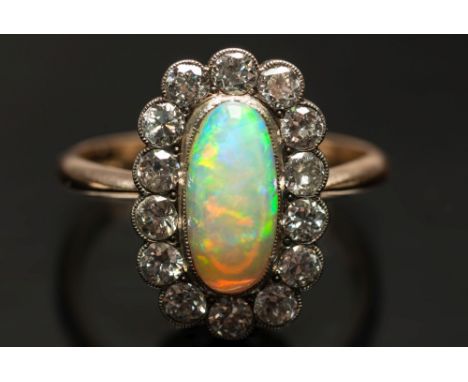 An opal and diamond oval cluster ring:, the central opal approximately 12mm long x 6mm wide within a surround of round brilli