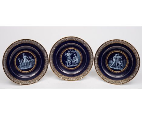 Three Meissen porcelain plates: each of circular form with pierced rim, the centre decorated in white enamel on a cobalt blue