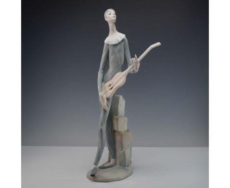 Matte finish, early Lladro porcelain piece posed harlequin style figure in a pale blue diamond patterned costume, in a wistfu