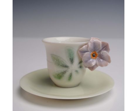 Exquisite porcelain cup and saucer set features a delicate design with a lavender flower accent adorning the handle. The cup 