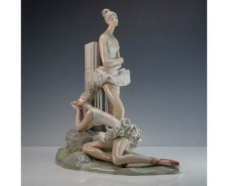 This graceful porcelain sculpture captures the quiet elegance of two ballerinas sharing a serene moment of rest. One stands p