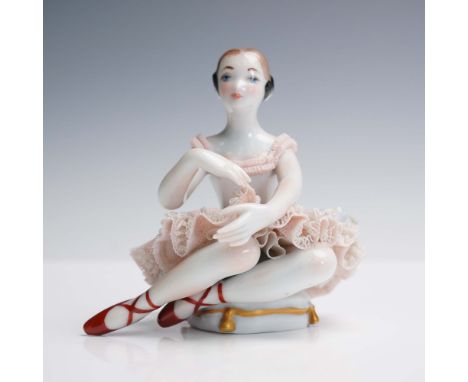 This delicate porcelain figurine by Lladro depicts a seated ballerina in a soft pink lace tutu with finely painted features a
