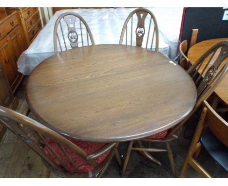 An oval Ercol medium oak extending dining table with fold away centre leaf together with a pair of dining chairs with swan ba