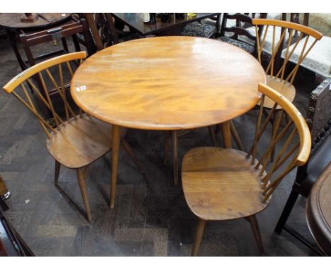 A circular light Ercol dining table together with four matching stick back chairs   All in need of renovation 