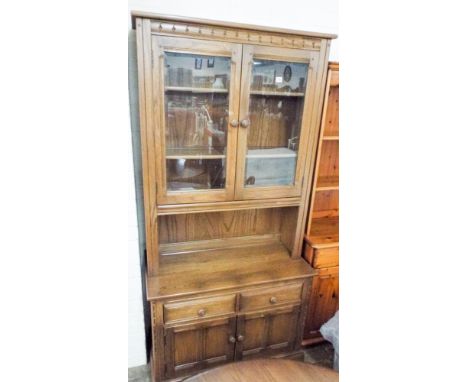 An Ercol medium oak glazed two door bookcase standing on a drawer and cupboard base 3' wide 