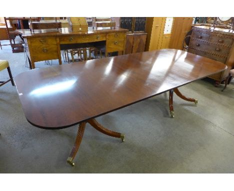 A 20th Century mahogany double pedestal dining table in the Regency style, each pedestal having four outswept supports, 277cm