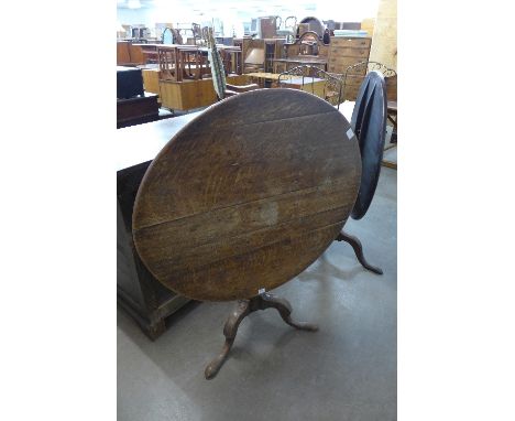 A George III oak circular tilt top table with baluster turned column on tripod supports