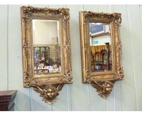Pair of gilt-composition mirrors, with bevel plates and shelves with moulded cherub below