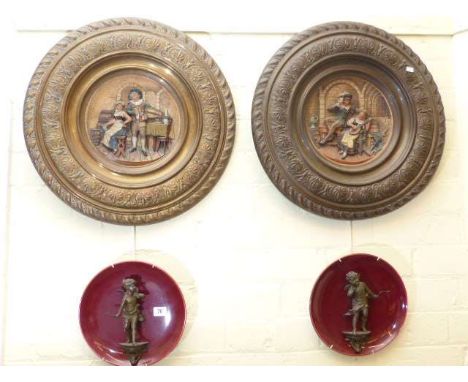 Pair of circular metal plaques decorated with classical scenes and pair of plates fitted with spelter cherubs