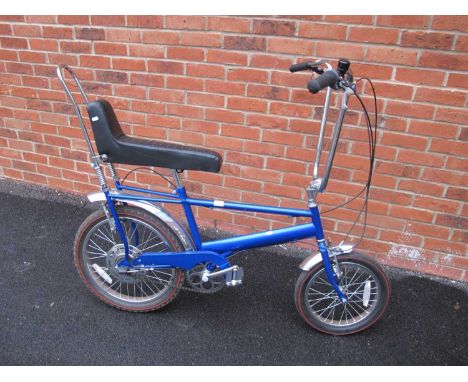 A Ground Cruiser bike (Raleigh Chopper replica) marked to back, in blue, featuring three gears and kickstand.