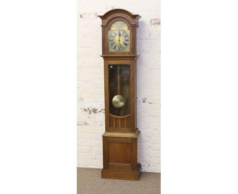 A 1930s light oak eight day longcase clock with brass arch top dial and Westminster chime.