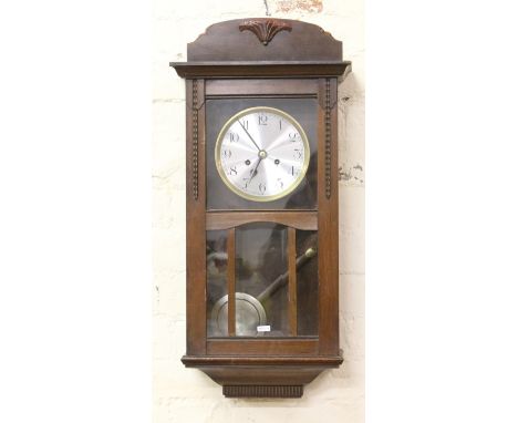 An oak cased eight day wall clock chiming on a coiled gong.