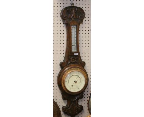 A carved oak cased banjo barometer incorporating a mercury thermometer.