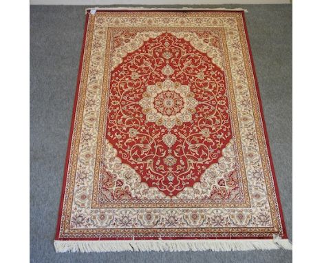 A Keshan style carpet, with a central medallion and foliate designs, on a red ground, 130 x 160cm