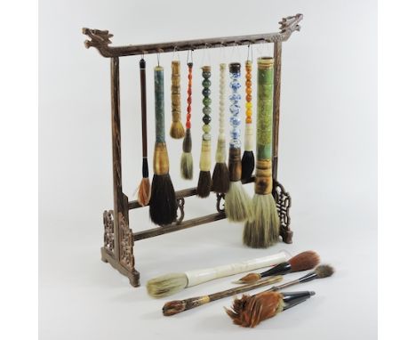 A collection of various Chinese calligraphy brushes, to include hardstone handled examples, on a carved hardwood stand, surmo